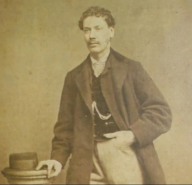 Sepia studio portrait of a young man in a long coat, said to be Curly Bill Brocius